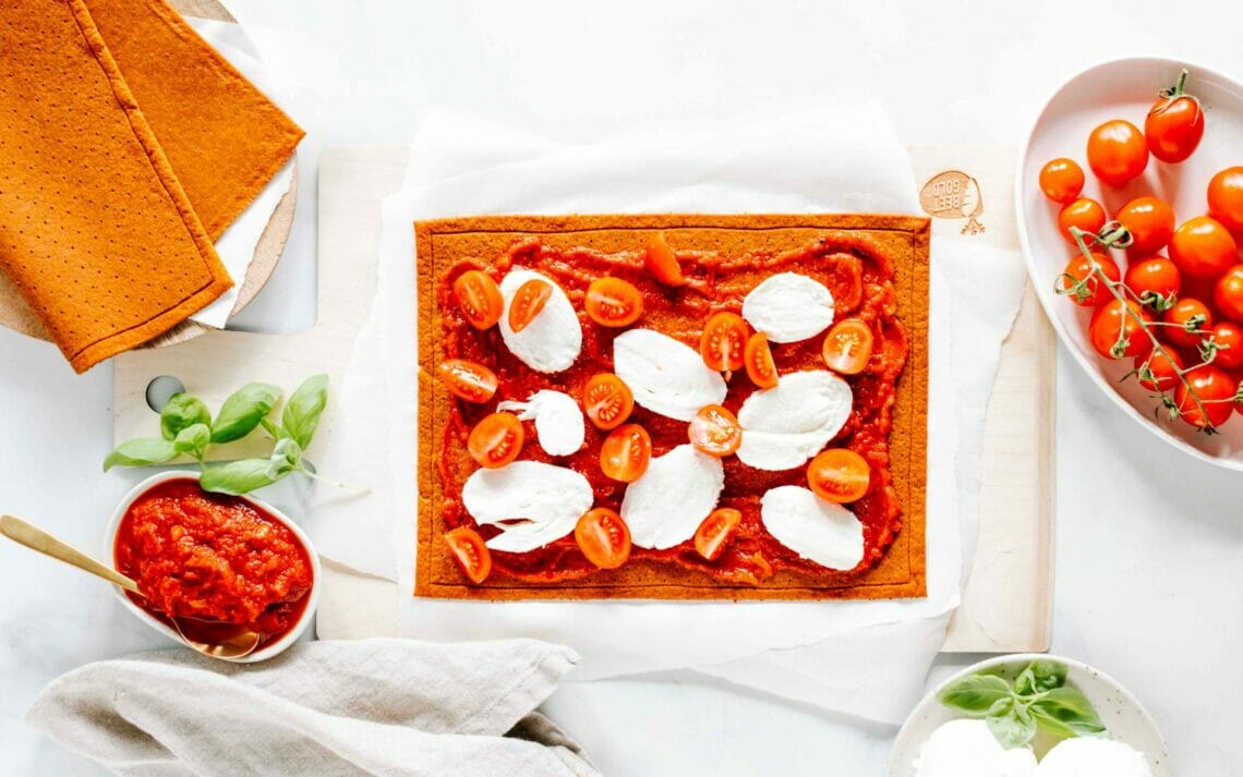 Gemüse Pizzaboden belegt mit Tomatensauce, Cocktailtomaten und Mozzarella